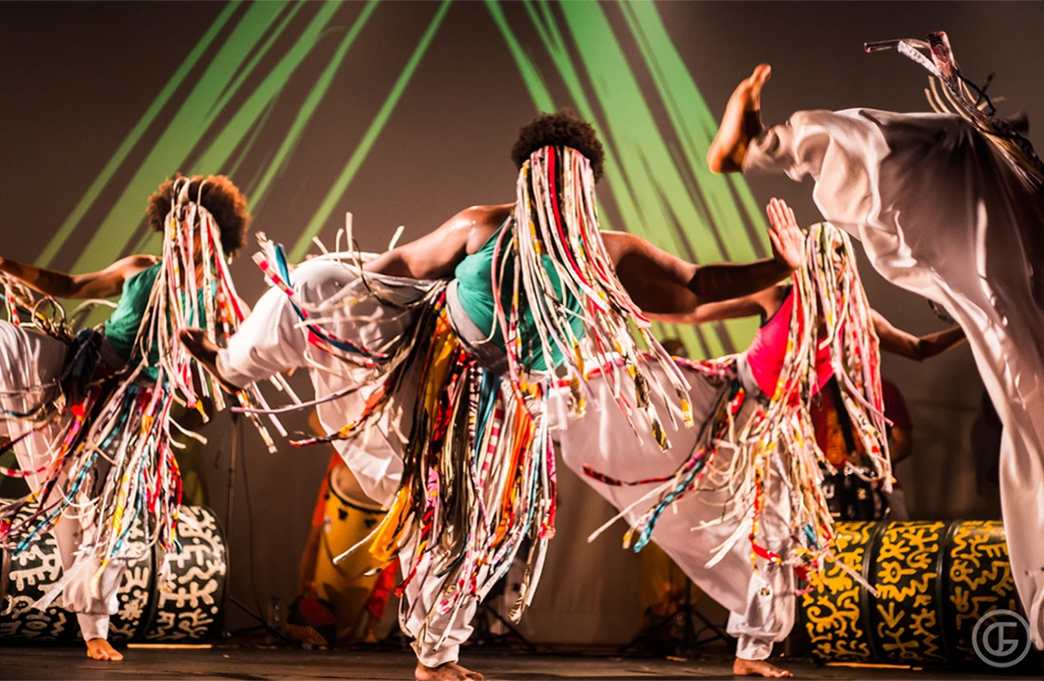 Apresentação ao vivo da Cia Treme Terra, com dançarinos realizando uma coreografia de inspiração afro-brasileira.